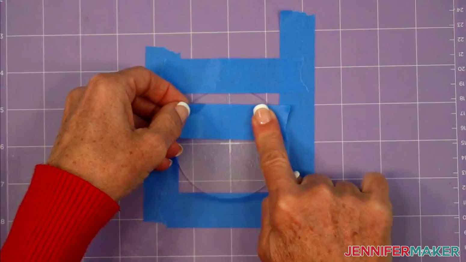 The acrylic blank is still attached to the purple strong grip mat with painters tape and another piece of painters tape is being used to remove the acrylic shavings.