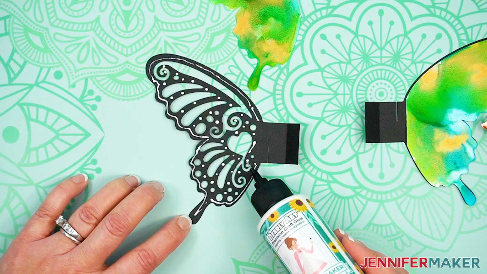Add glue to the front of the bottom butterfly wing piece, avoiding the tab and cutouts.