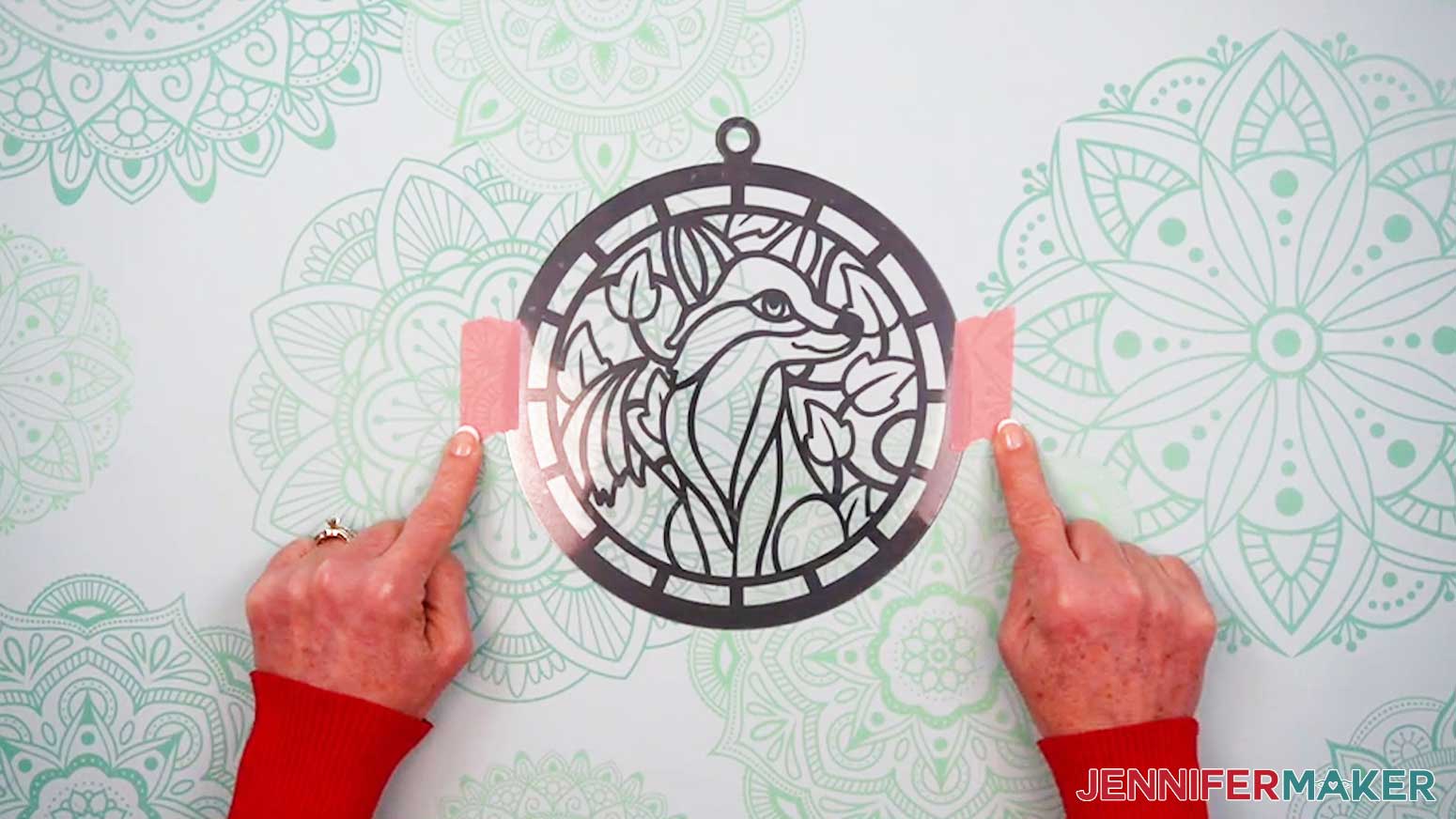 Use painter tape to adhere the stack of acetate and vinyl pieces for the Alcohol Ink Stained Glass design to the work surface.