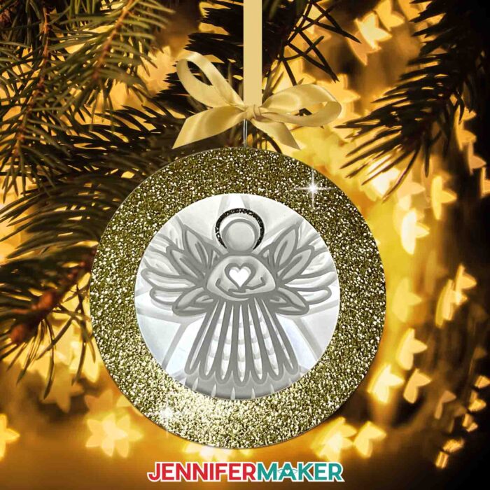 Learn how to make an angel shadow box ornament with Jennifer Maker's tutorial! A beautiful papercrafted angel shadowbox ornament hangs from a glowing Christmas tree.