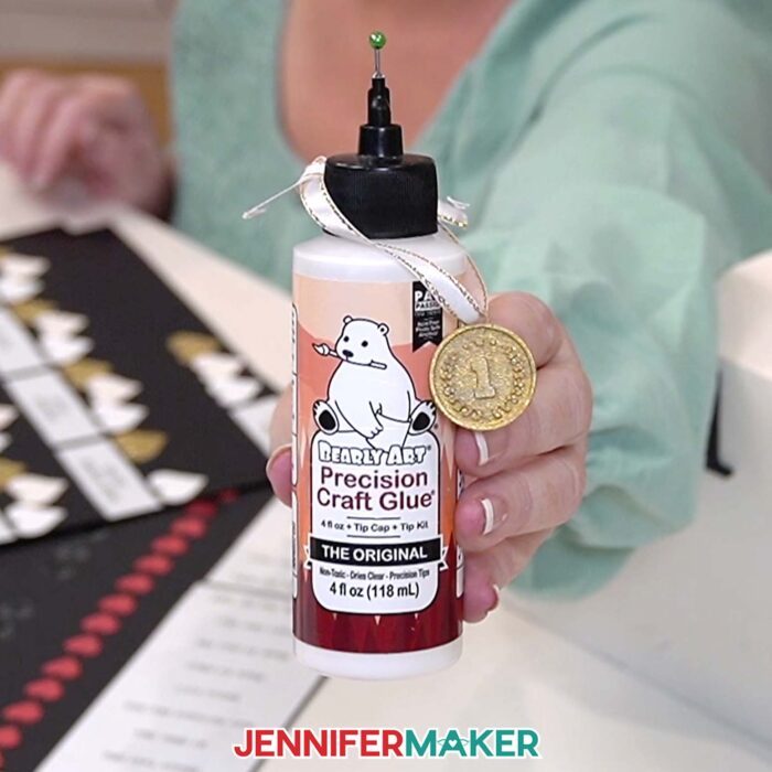 Jennifer holding up a bottle of Bearly Art Precision Craft Glue with a Gold #1 Medal around it. This is Jennifer's favorite of the best craft glues.