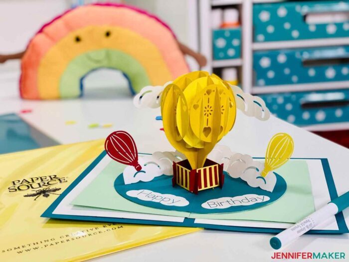 Colorful open hot air balloon birthday card pop up design on a desk.