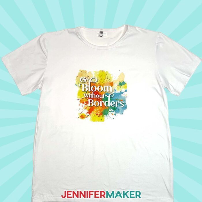 A white T-shirt sublimated with the words "Bloom without Borders" on a colorful splash background.