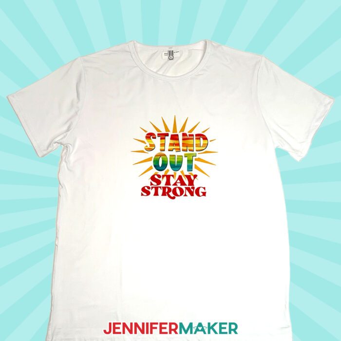 A white t-shirt with the words "Stand Out, Stay Strong" sublimated across the front in bright colors.