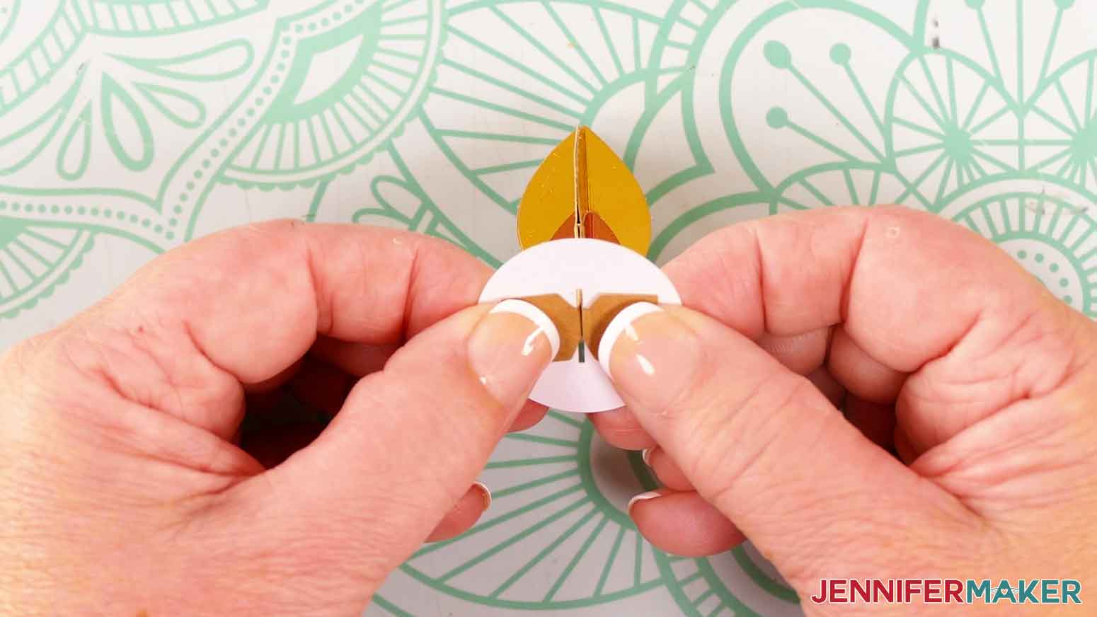 Fold the rectangular tabs up and press them against the underside of the circle piece.
