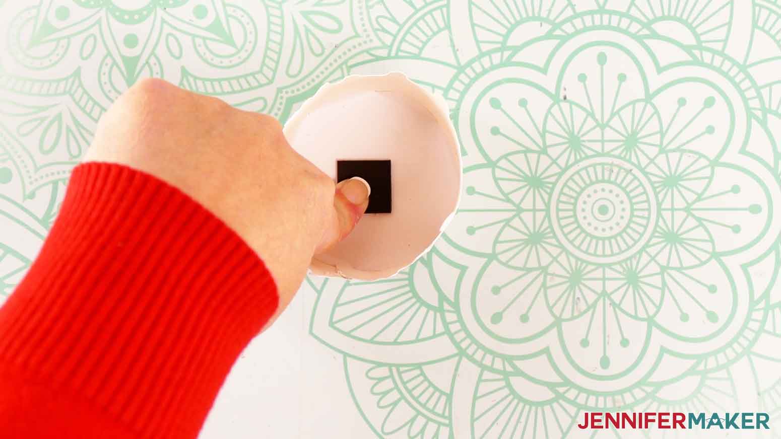 Press the sticky side of the magnetic square onto the inside top of the candle’s lid.