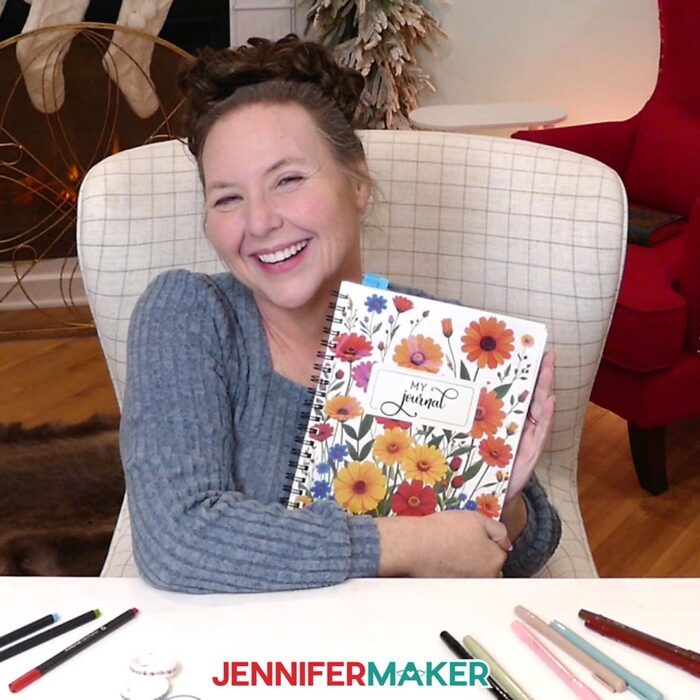 Jennifer holds up a notebook with the words "My Journal" on a background of wildflowers for the cover.