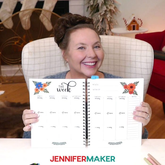 Jennifer holds open her custom Canva journal to show weekly calendar pages.