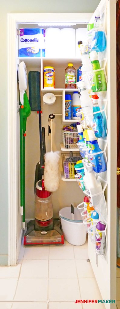 A well stocked and organized cleaning closet with light, door holder, bag holders, and broom holders