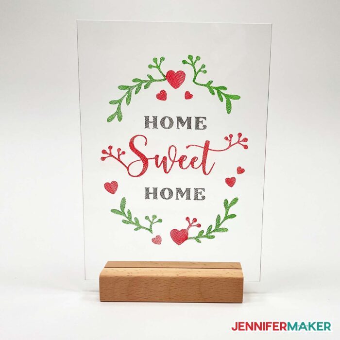 Enamel paint color engraving Home Sweet Home design on a clear acrylic plaque in a wooden stand.