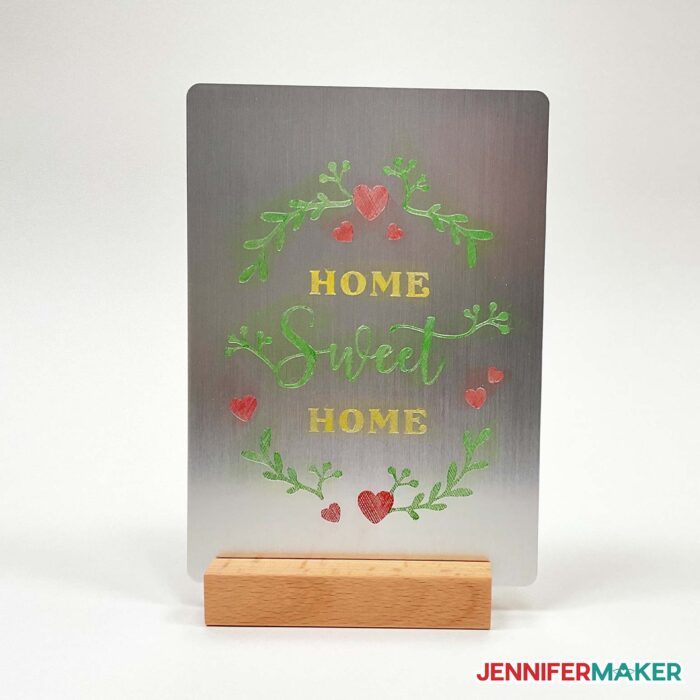 Enamel paint color engraving Home Sweet Home design on a metal plaque in a wooden stand.