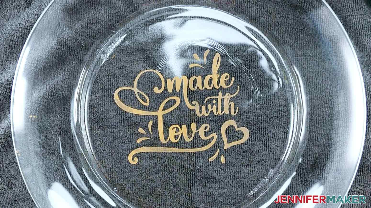 An overhead photo showing a finished color glass etching plate project with an etched design that says "made with love" painted in gold