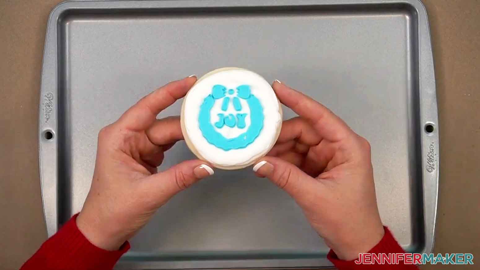 The completed cookie is shown held up with the wreath design visible.