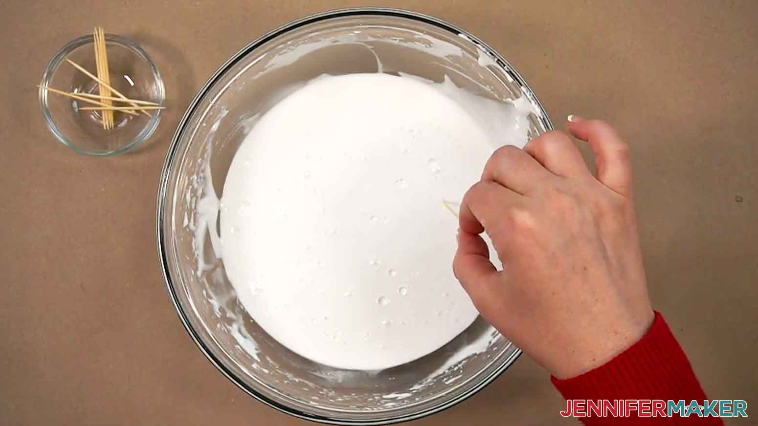 The flood icing is shown and a toothpick is being used to pop any air bubbles on the top of the icing.