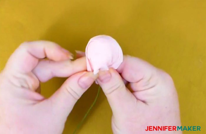 Wrapping a crepe paper circle around a crepe paper ball to form a crepe paper peony bud