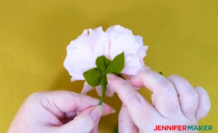 Gluing on a leaf on the underside of a crepe paper peony flower