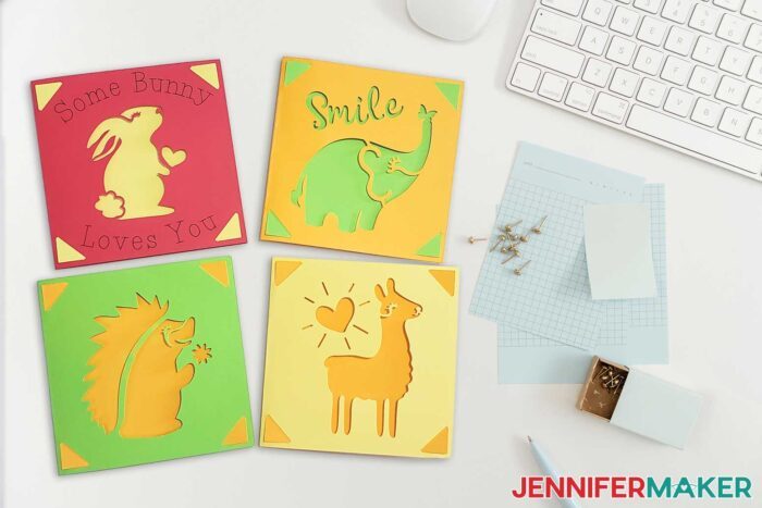 Cardstock Cricut cards in red, orange, green, and yellow with animal designs on a desk