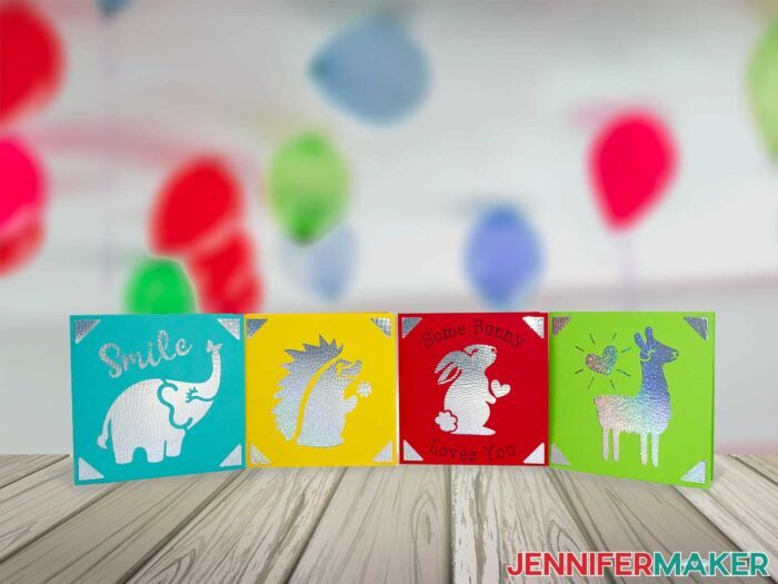 Square Cricut Cards on a table in multiple colors with balloons in background
