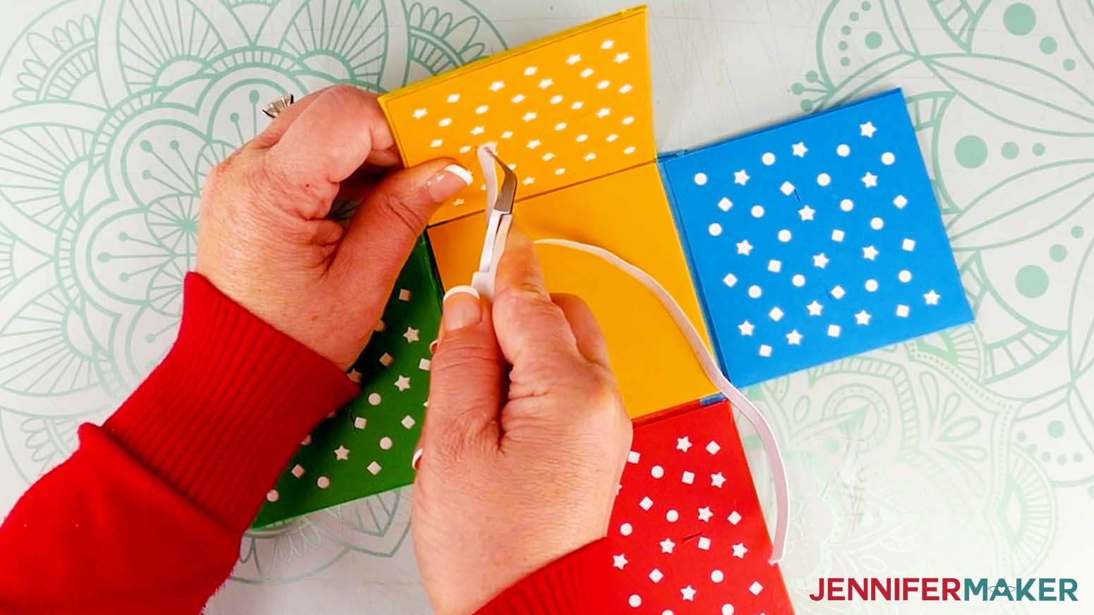 Use tweezers to push the end of the elastic through a slit on a decorated panel of the cardboard jumping box