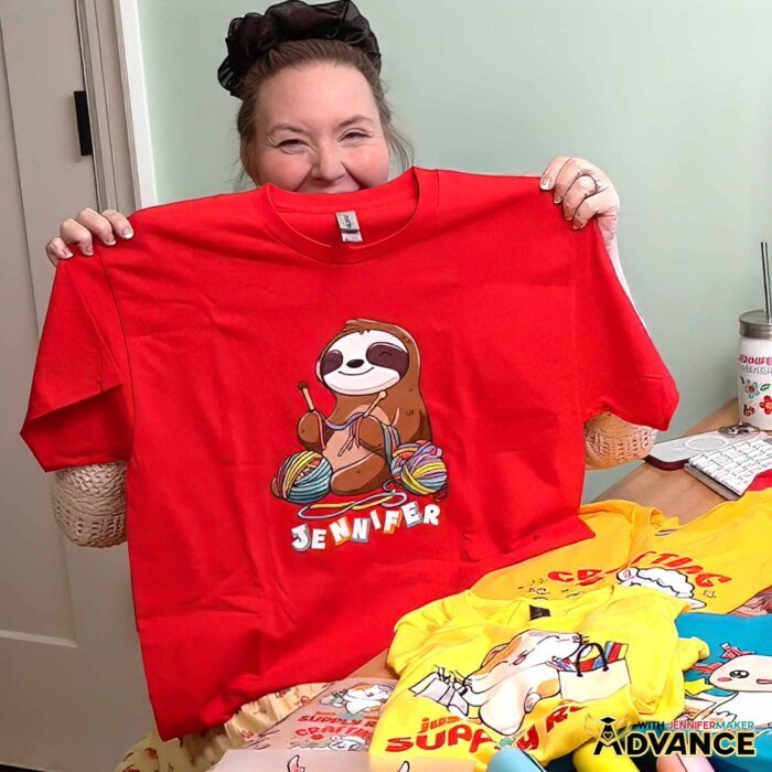 Jennifer Maker shows off a T-shirt decorated with one the Cricut DTF Transfers she ordered from Cricut Design Space, featuring a cute crafting sloth design