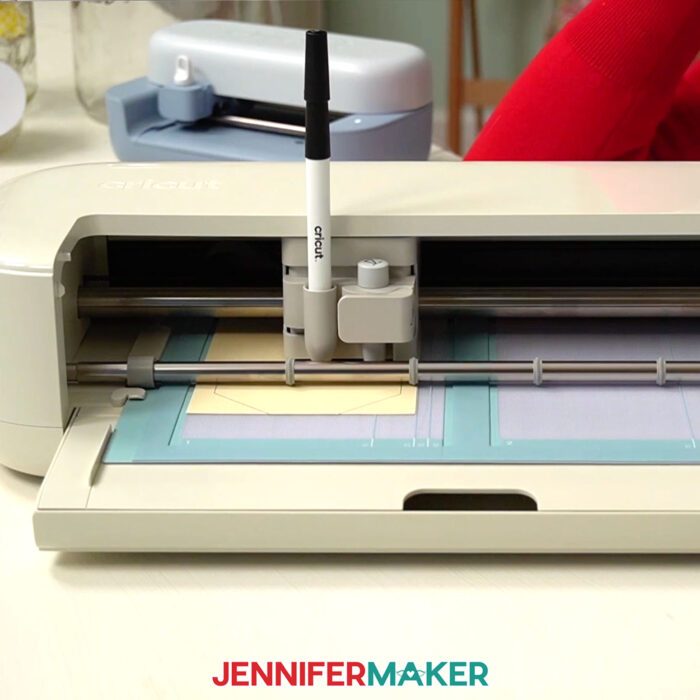 A Cricut Explore 5 drawing on paper using a card machine mat.