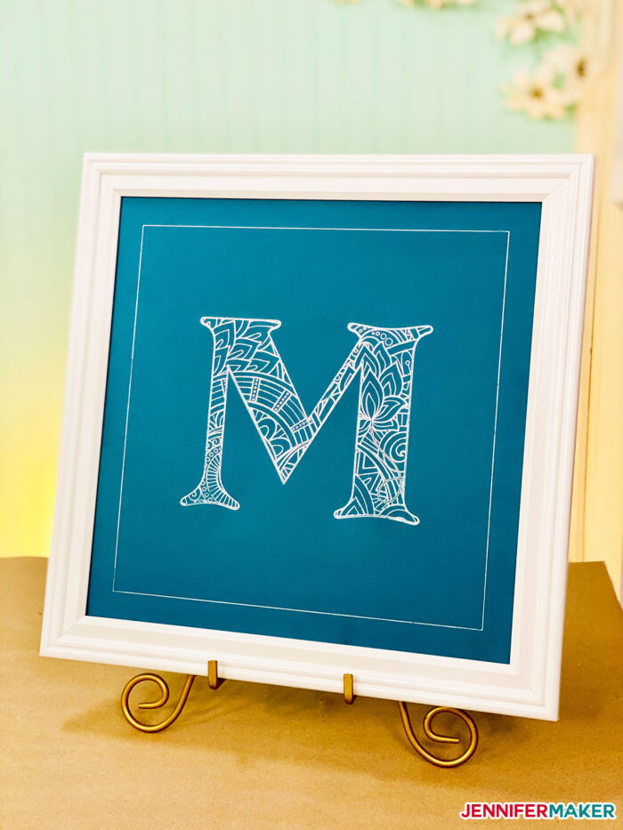 Beautiful foil mandala letter in silver foil on blue cardstock with a white frame