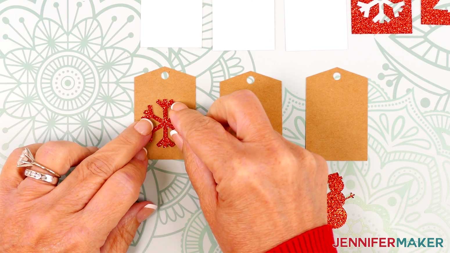Adhere the small glitter snowflake piece to the kraft tag in the Cricut Gift Wrapping Ideas project.