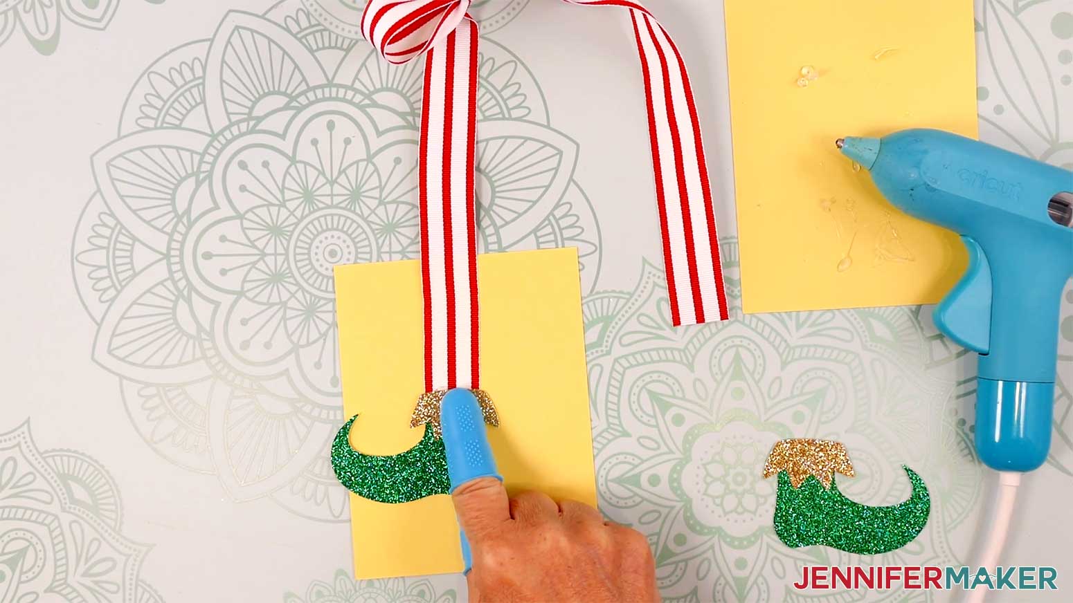 Adhere the elf boots to the front of the ribbon tails in the Cricut Gift Wrapping Ideas project.