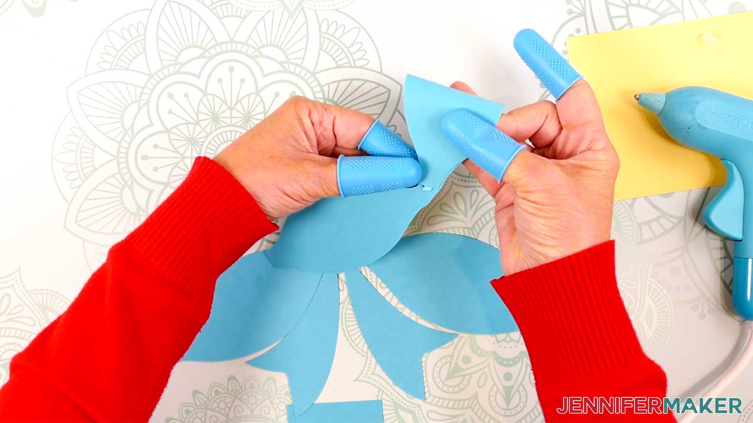 Curve one side of the Fancy Paper Bow's top loop down and press it into the hot glue in the Cricut Gift Wrapping Ideas project.