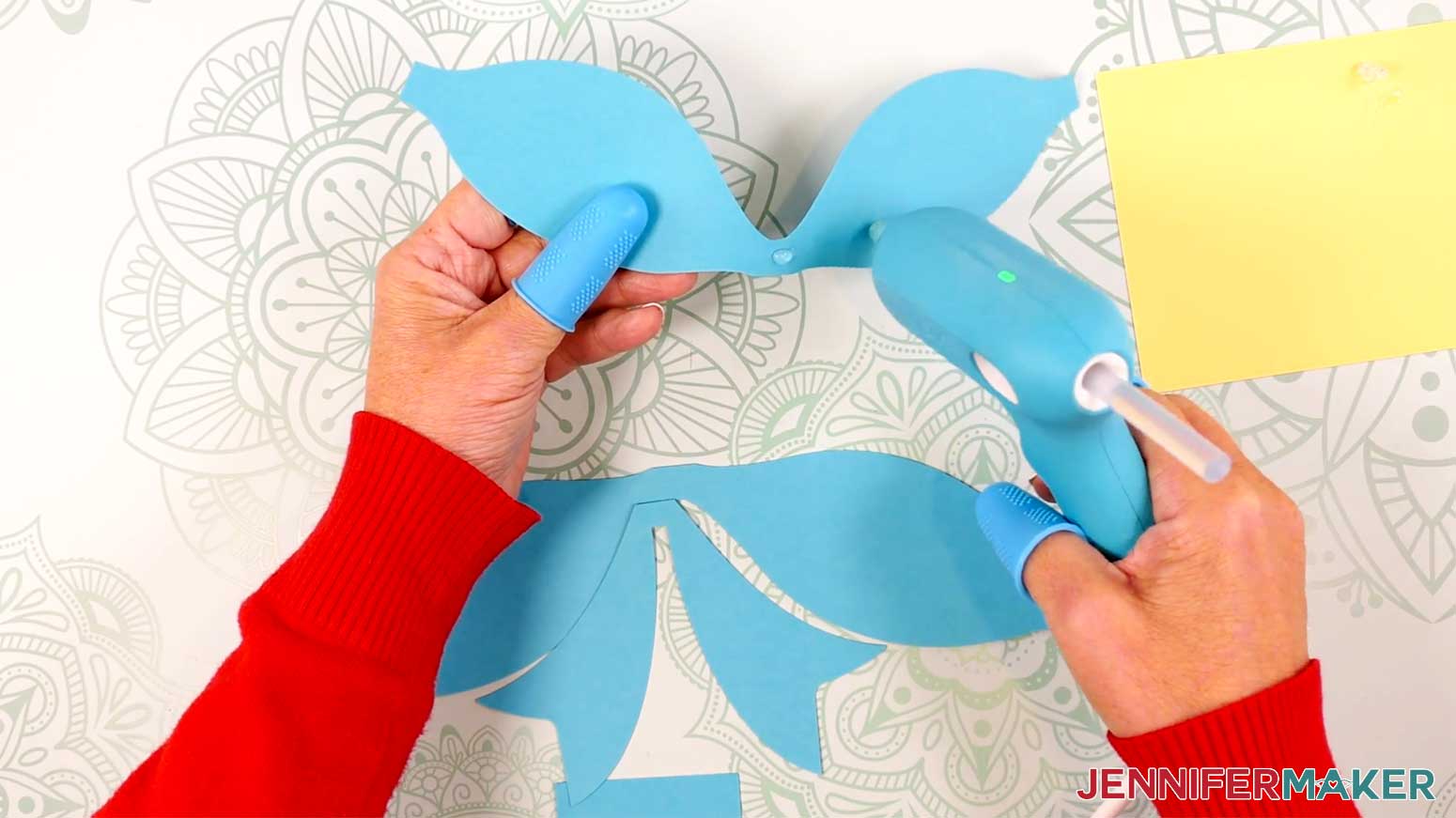 Apply hot glue to the middle of the top loop of the Fancy Paper Bow in the Cricut Gift Wrapping Ideas project.