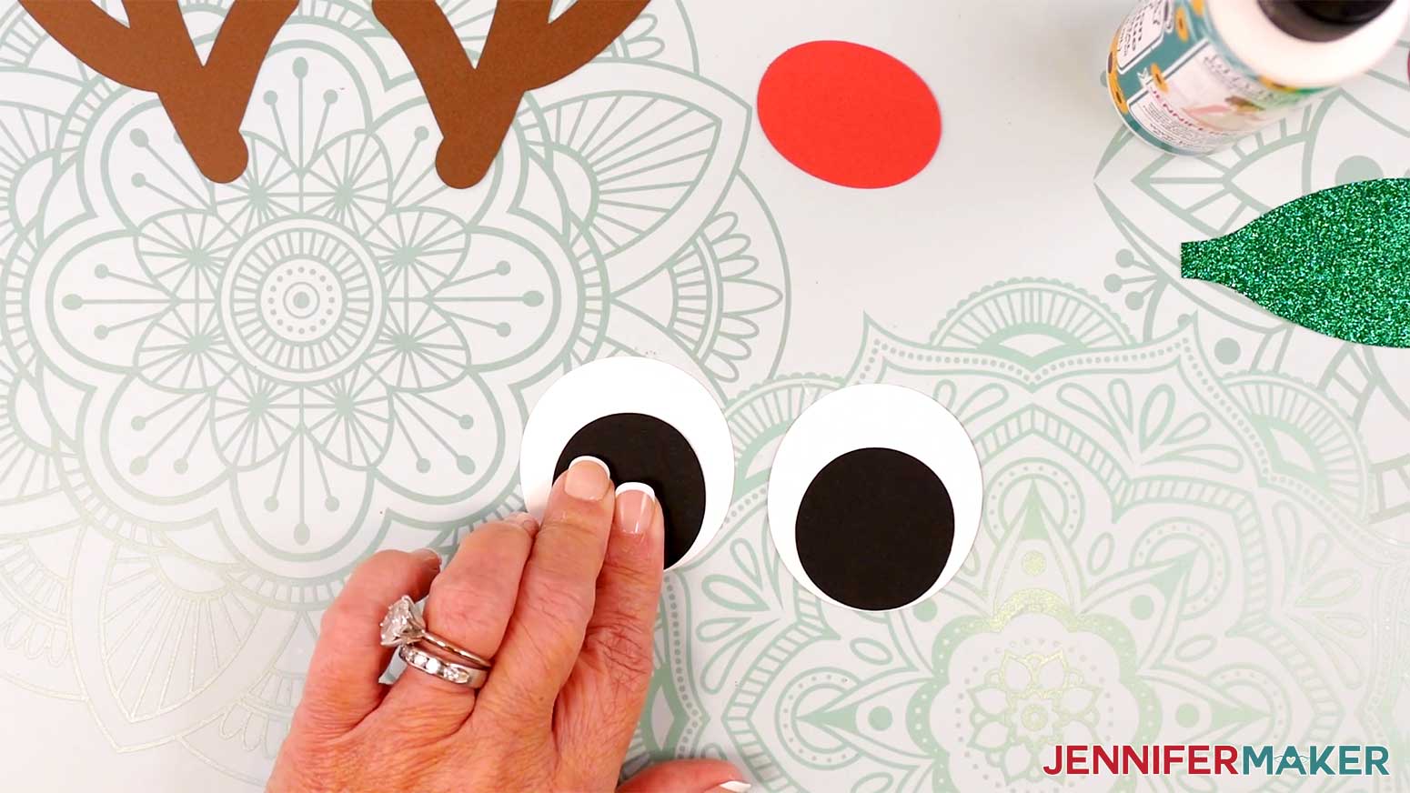 Adhere the black eye piece at the bottom edge of a white eye piece for the Reindeer Gift Bags in the Cricut Gift Wrapping Ideas project.