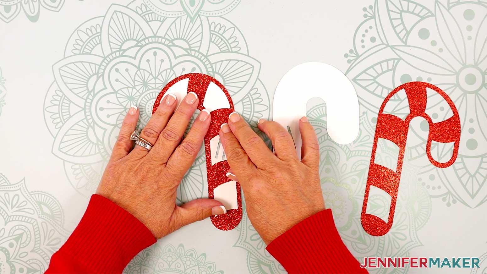 Attach the striped red candy cane layer to the front of a solid white candy cane layer, keeping edges and slit cutouts aligned.