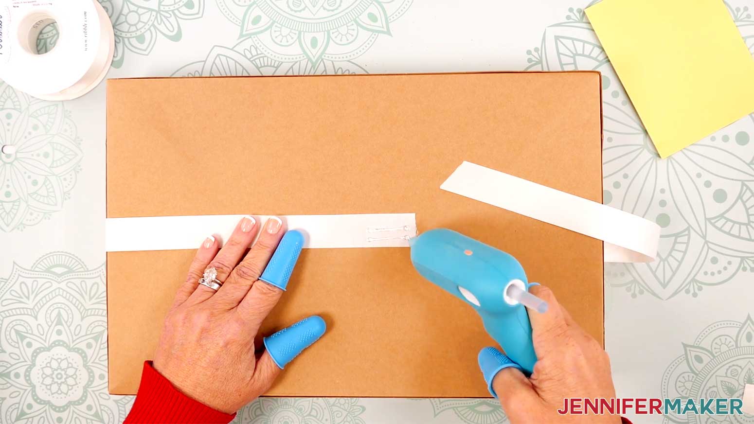 Wrap the ribbon around the box and secure its ends to the package with hot glue.
