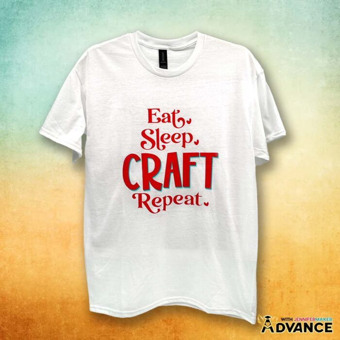 A white T-shirt with a layered red and teal vinyl decal says "Eat, Sleep, Craft, Repeat." Learn how to make T-shirts like these in my Cricut Iron-On Vinyl Tutorial