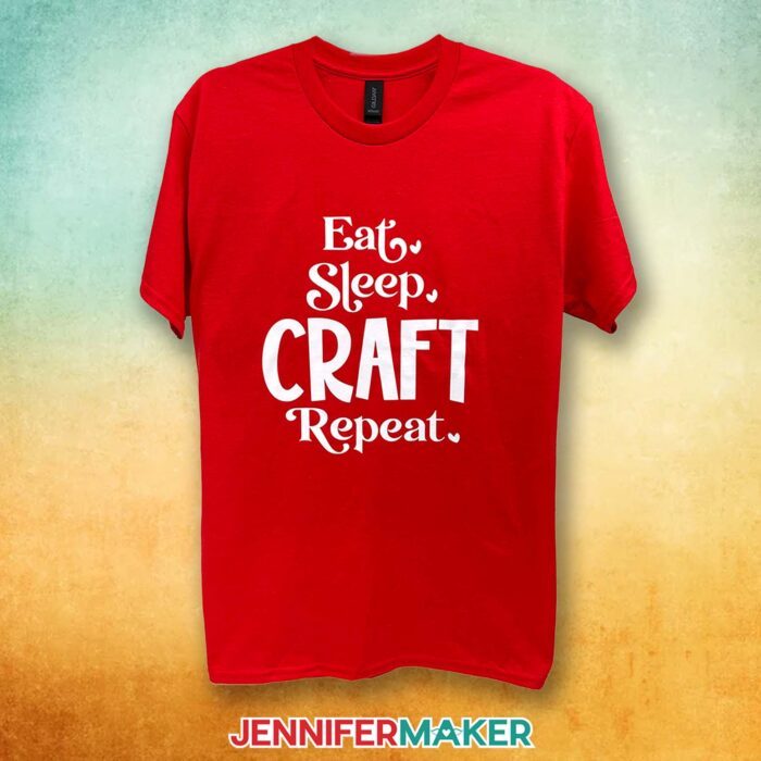 A red T-shirt with a white vinyl decal says "Eat, Sleep, Craft, Repeat." Learn how to make T-shirts like these in my Cricut Iron-On Vinyl Tutorial