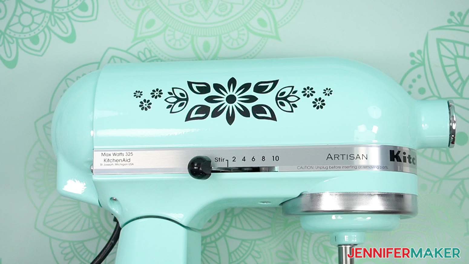 A black floral adhesive vinyl design applied to the side of a blue kitchen stand mixer.