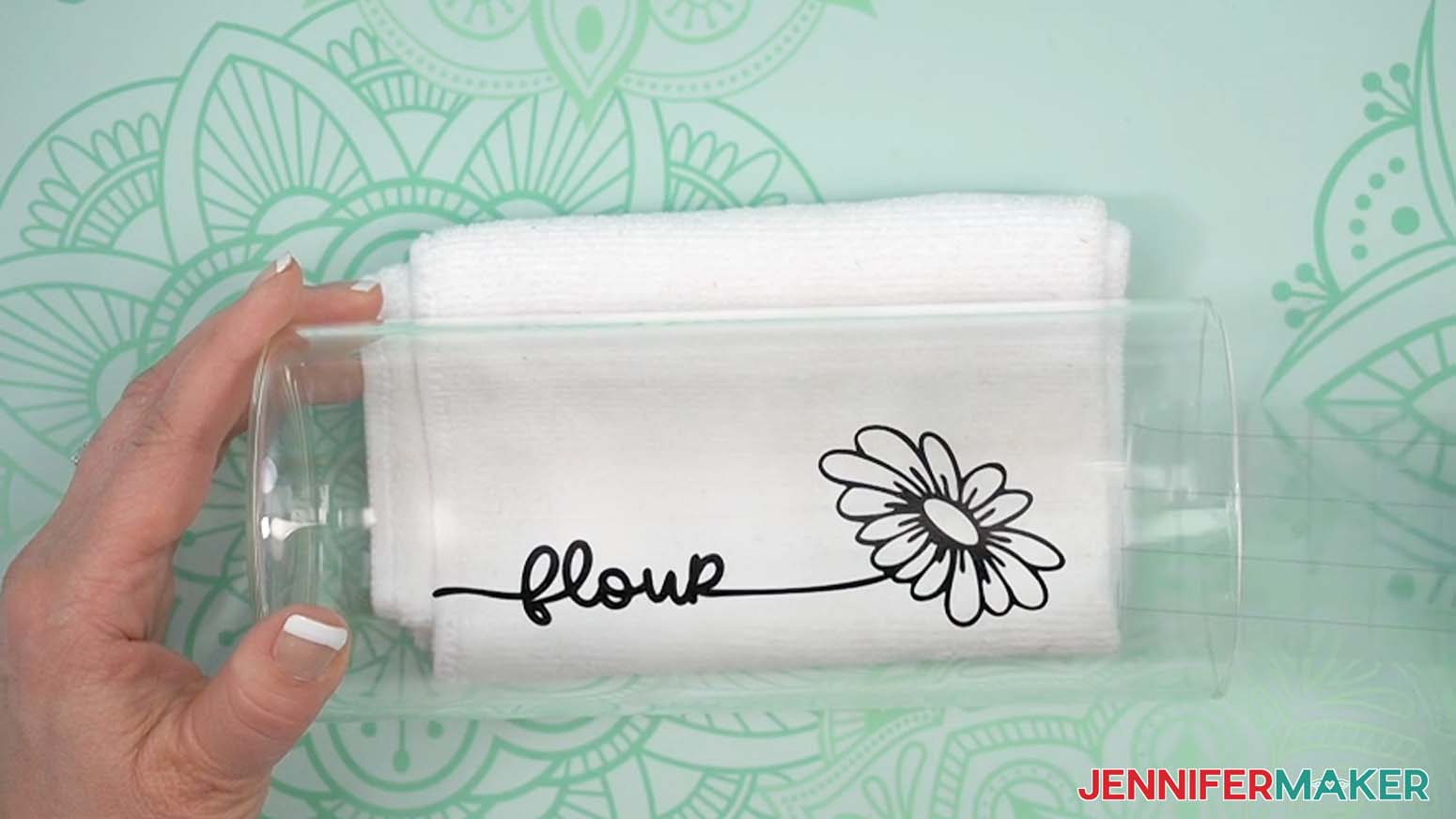 A black adhesive vinyl design that says "flour" applied to the side of a glass jar.