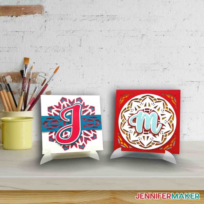 Layered Cricut Mandalas with initials in reds and blues on a desk