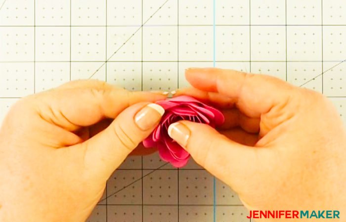 Holding the rolled paper flower in place while the glue dries to create a Cricut paper flower