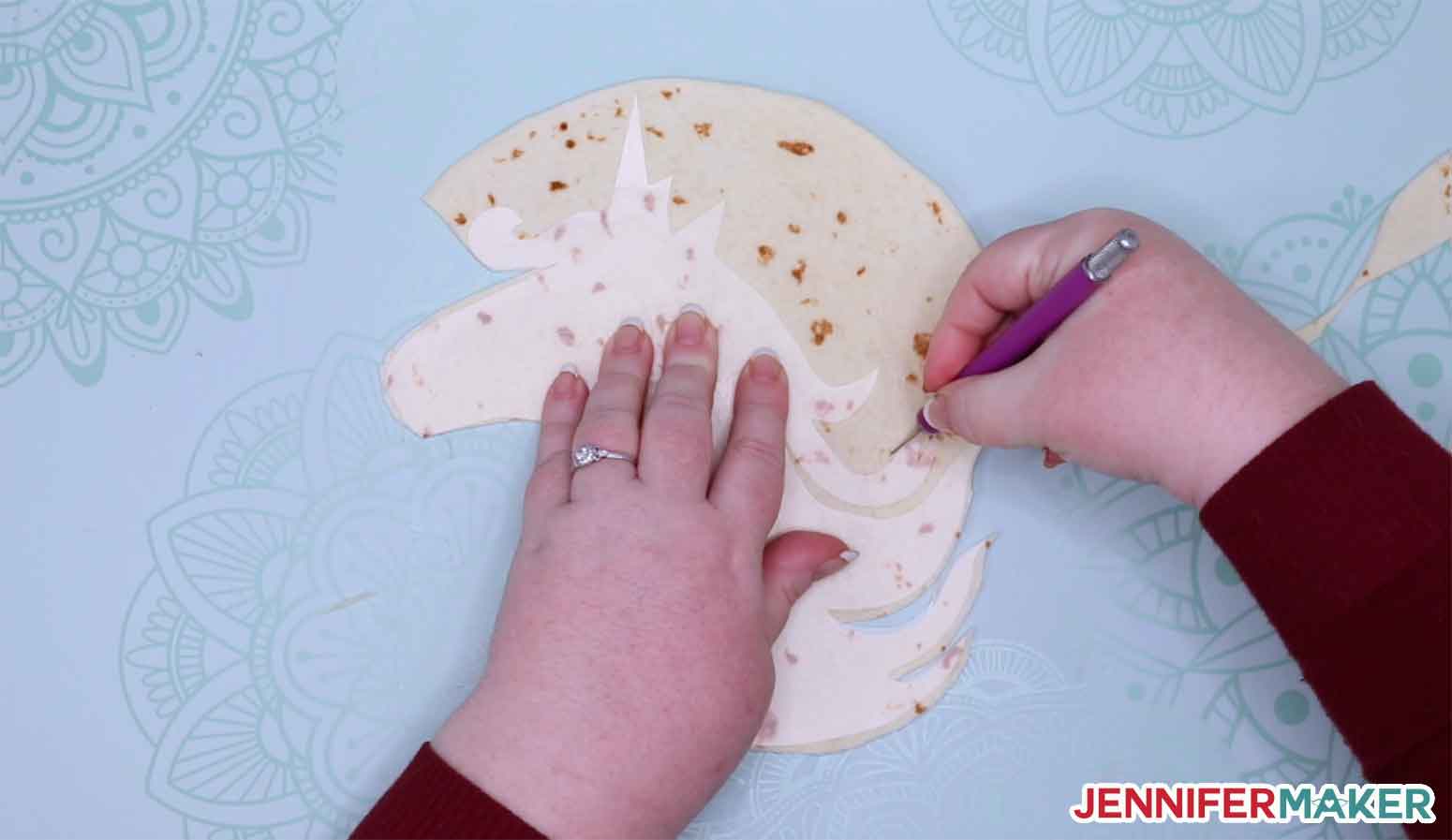 Cutting the tortilla with a knife using the Cricut stencil cut from plastic