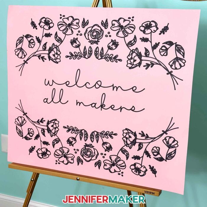 Pink cardstock sign with Welcome All Makers in marker made with the Cricut Venture large format cutting machine.