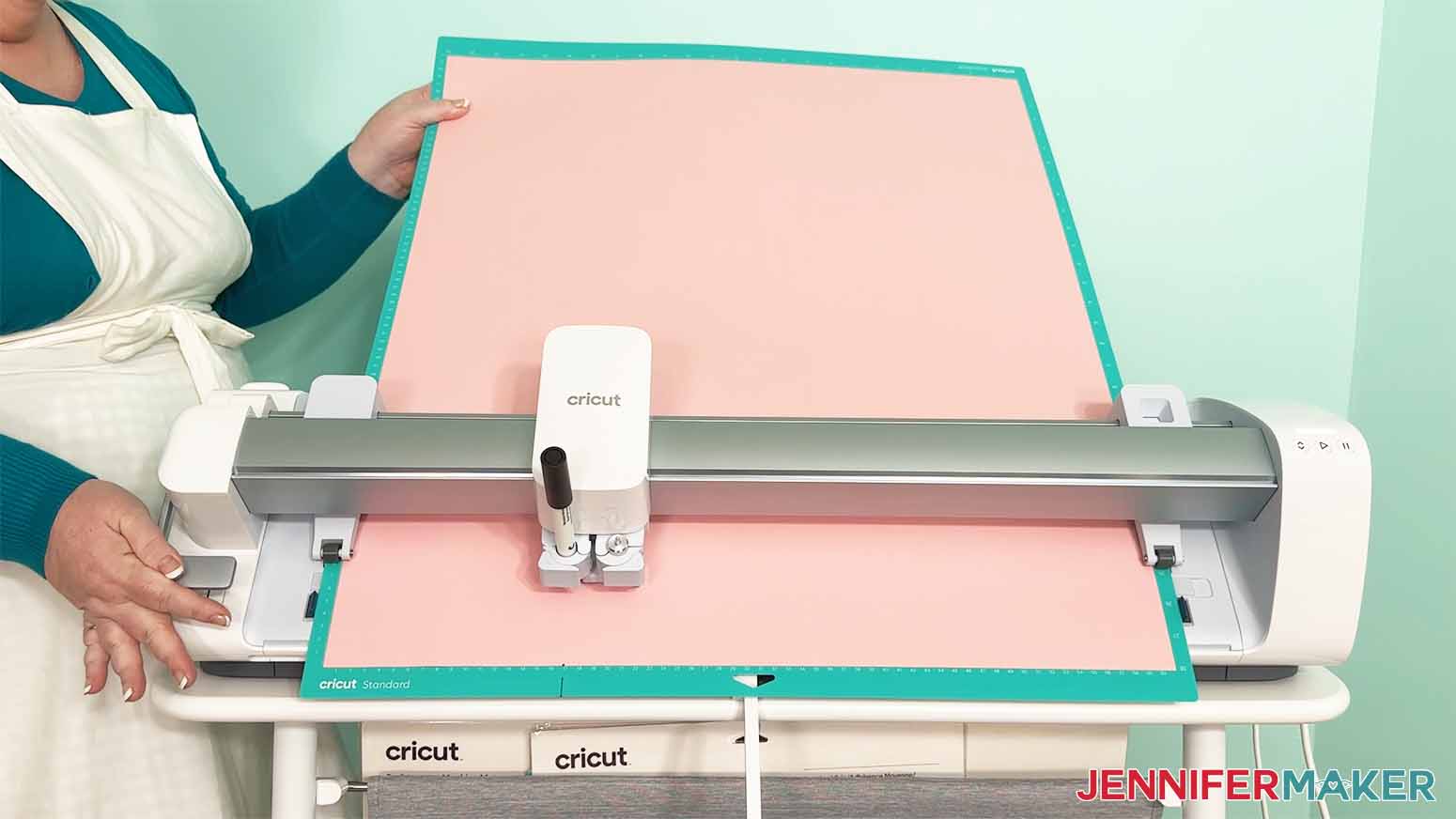 Jennifer Maker feeding a Performance mat with pink cardstock in to a Cricut Venture large format cutting machine.