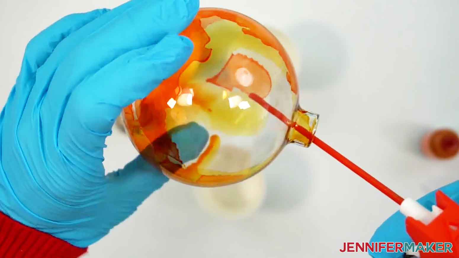 After several drops of yellow ink are added to the ornament, use the compressed air to spread the ink.