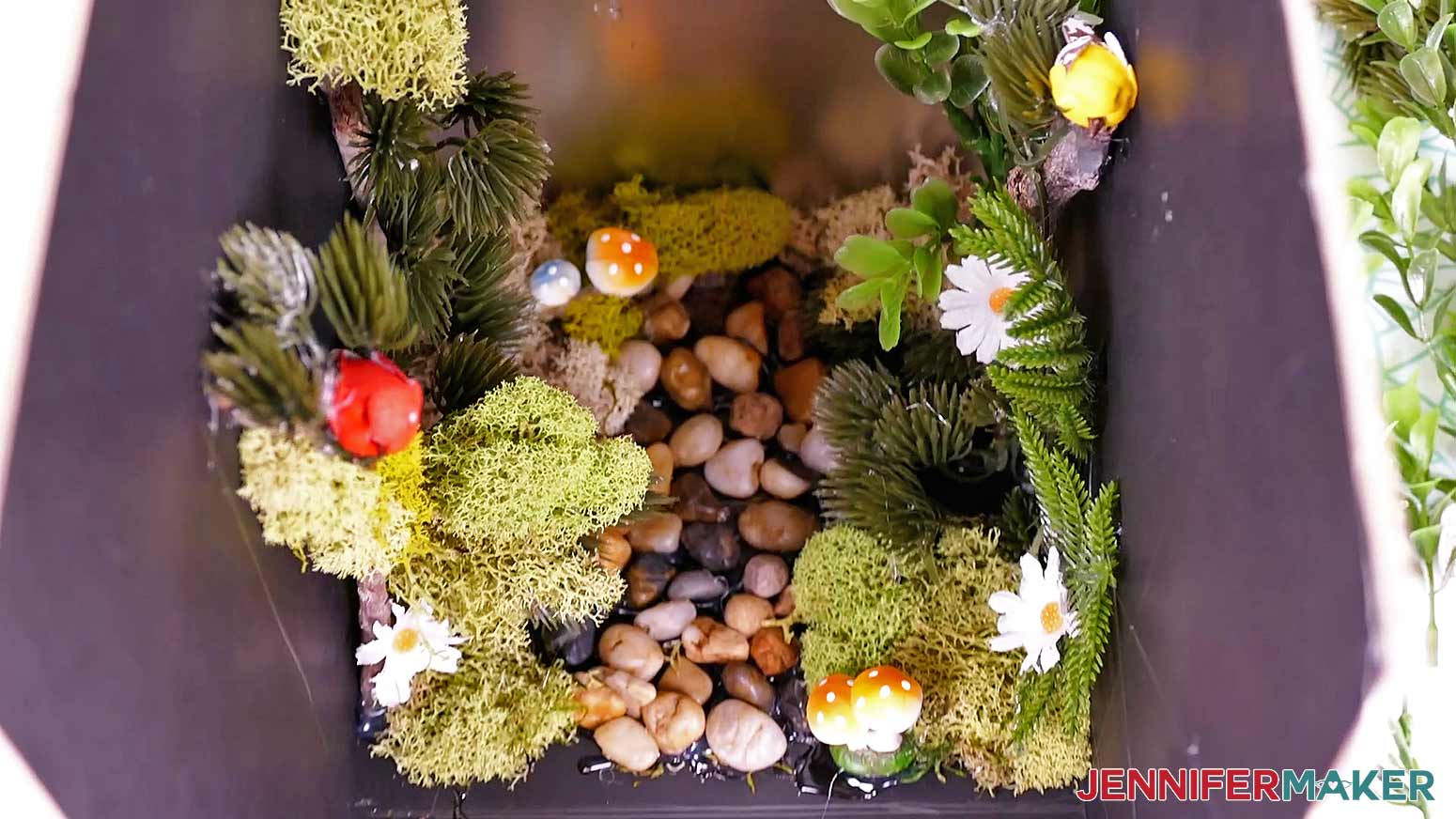 Rocks, branches, moss, floral stem pieces, and miniatures attached to the inside of the diy book nook