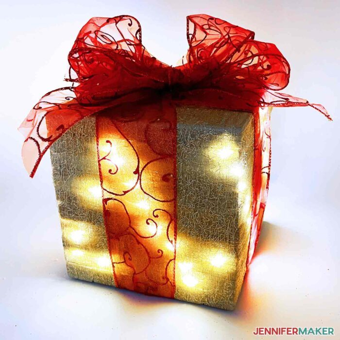 Large faux gift with a big red ribbon and lights for DIY Christmas decorations.