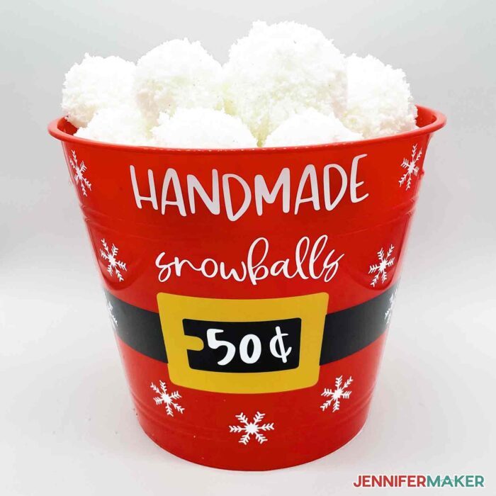 A big red bucket decorated using vinyl and full or fake snowballs for DIY Christmas decorations.