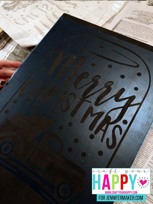 The stencil in place on the board for the DIY Christmas Mason Jar Snowglobe Chalkboard Sign