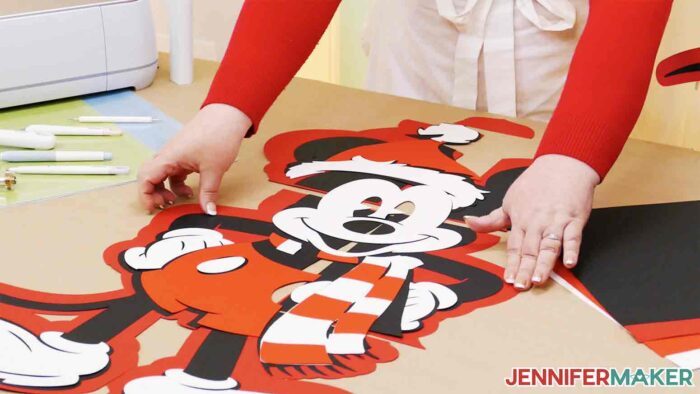 Jennifer Maker showing the different cardstock pieces taped together to make large DIY character cutouts of Mickey.