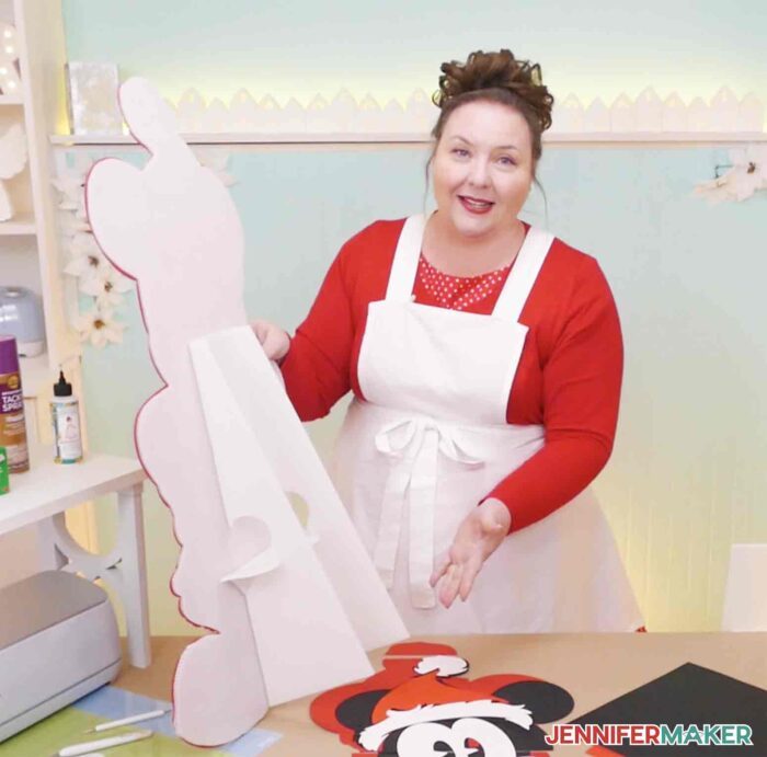 Jennifer Maker holding DIY cut out characters in craft room to show the stand made from corrugated white plastic.