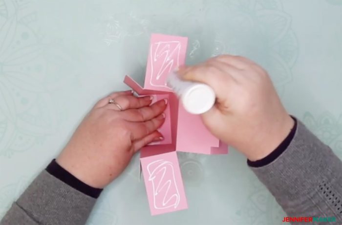 Glueing the sides on a pink piece of cut cardstock to make a DIY drawer divider